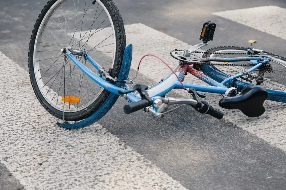 A bicycle lying on the road beside a marked crossing