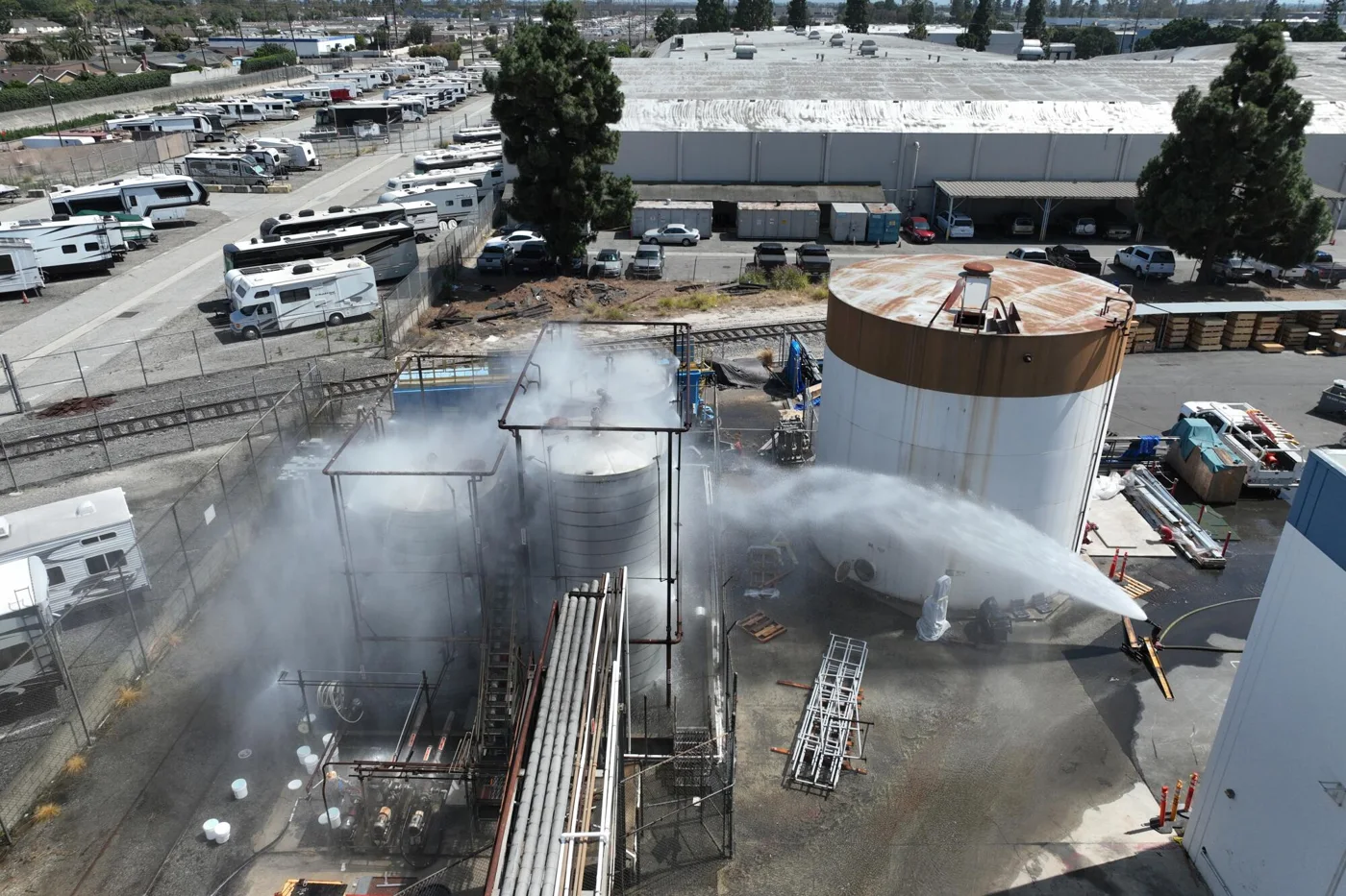 Emergency crews spraying water at an industrial storage tank