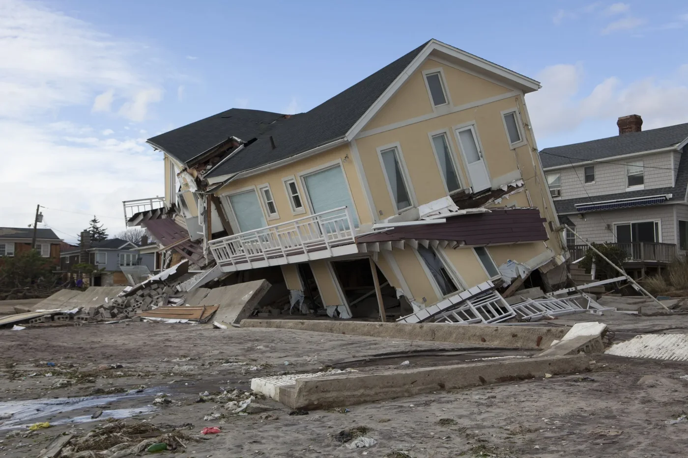 A severely damaged house with debris in the foreground