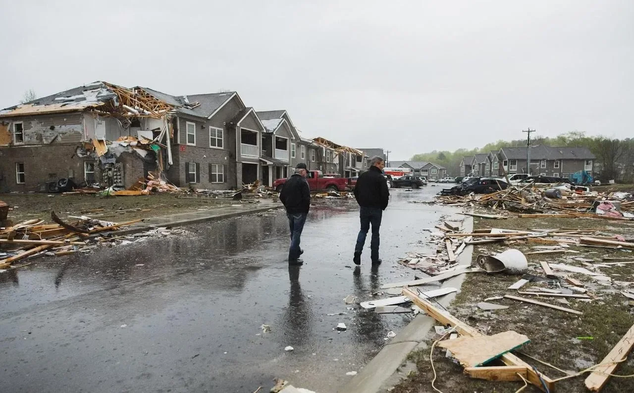 Two people walking through a storm-damaged neighborhood